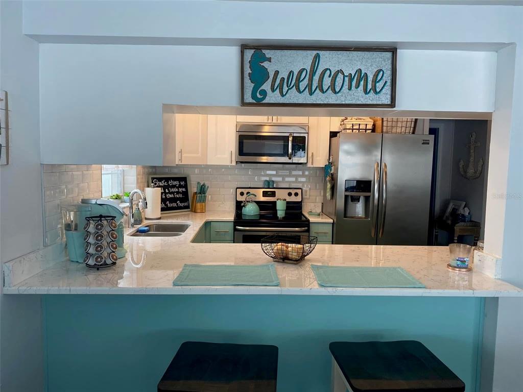 A kitchen features white cabinets, stainless steel appliances, and a breakfast bar with stools — 5240 SCHOOL ROAD, NEW PORT RICHEY, FL