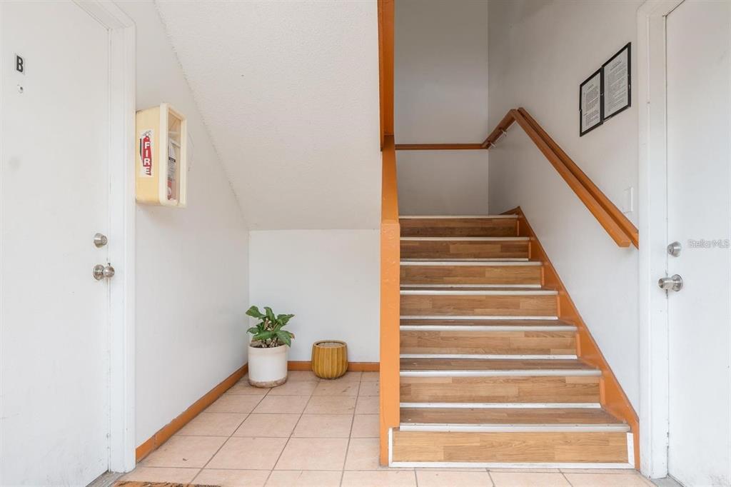 A tiled entryway features a wooden staircase with orange railings and a wall-mounted fire extinguisher — 1815 MICHIGAN AVENUE UNIT C, KISSIMMEE, FL
