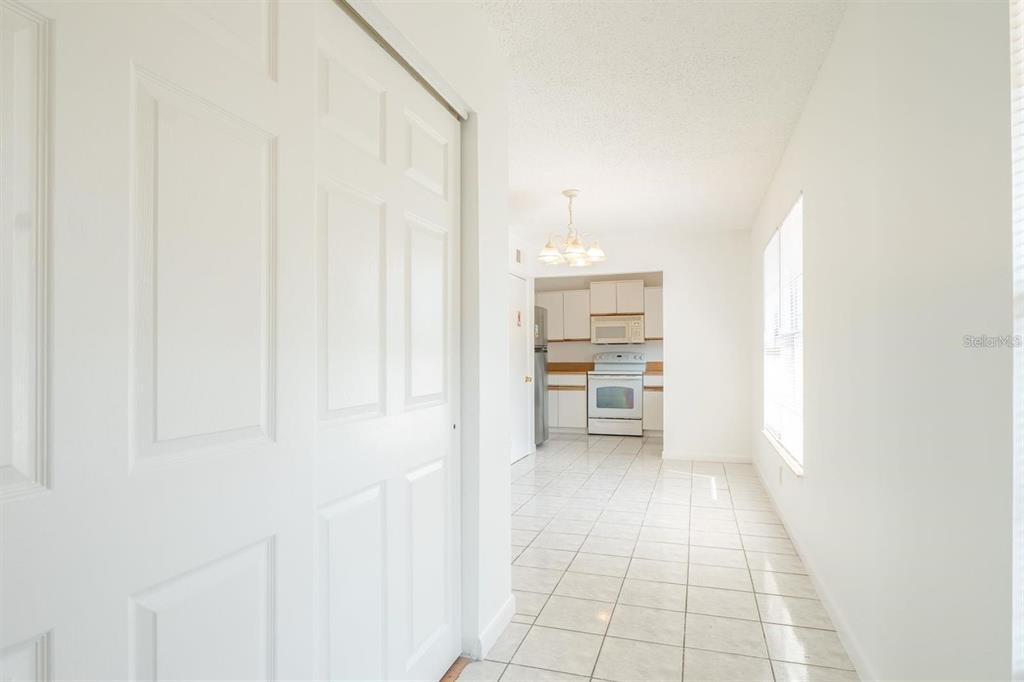 A tiled hallway leads to a kitchen with white cabinets and white appliances — 1815 MICHIGAN AVENUE UNIT C, KISSIMMEE, FL