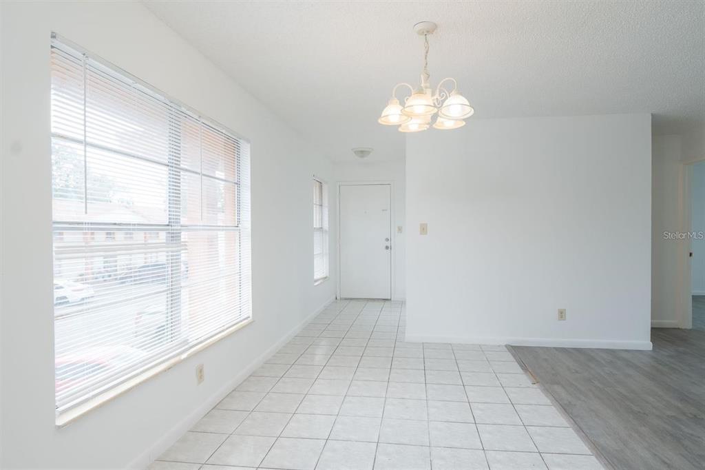 A bright dining area features white tile flooring, a chandelier, and a large window — 1815 MICHIGAN AVENUE UNIT C, KISSIMMEE, FL
