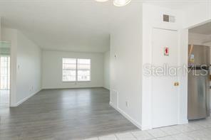 A view from a tiled kitchen area looking into a living room with gray flooring — 1815 MICHIGAN AVENUE UNIT C, KISSIMMEE, FL