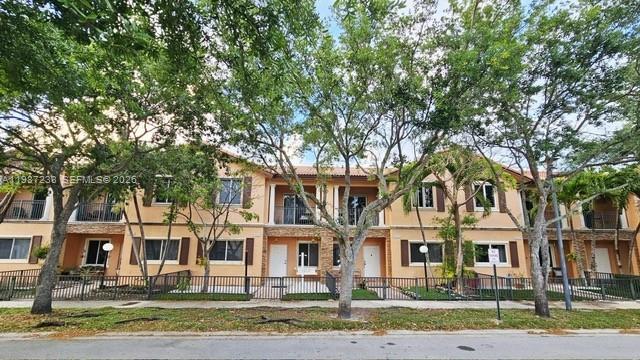 A multi-story tan townhouse complex features balconies, dark-framed windows, and a black metal fence — 11275 SW 231st Ln, Miami FL 33170, MIAMI, FL