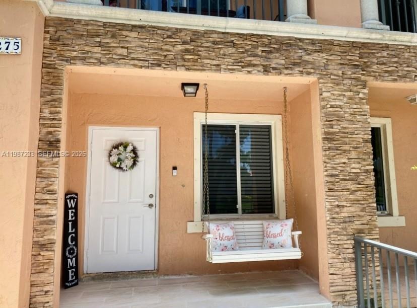 A white front door and a porch swing sit on a stone-accented patio — 11275 SW 231st Ln, Miami FL 33170, MIAMI, FL