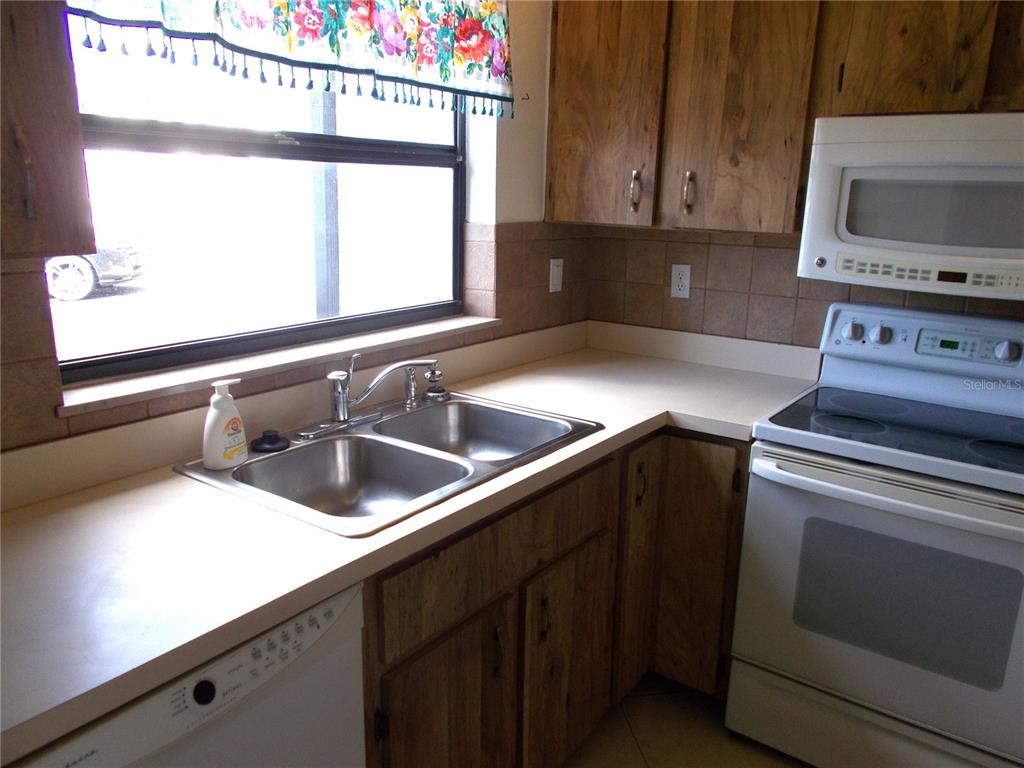 A kitchen features wood cabinets, a double-basin sink, white appliances, and a window with valance — 2000 FORREST NELSON BOULEVARD UNIT C6, PORT CHARLOTTE, FL