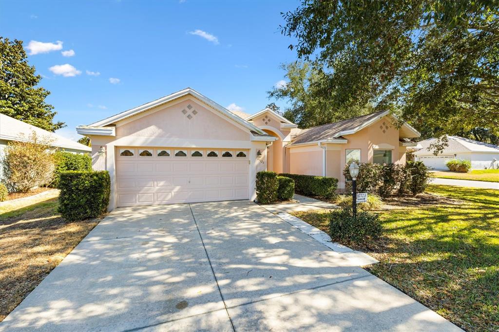 A single-story house with a light pink exterior, a two-car garage, and a concrete driveway — 17723 SE 81ST TIMBERWOOD TERRACE, THE VILLAGES, FL