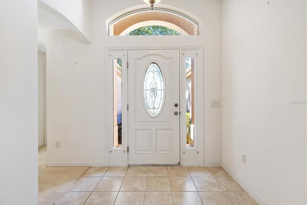 An entryway features a white front door with a glass insert, sidelights, and tile flooring — 17723 SE 81ST TIMBERWOOD TERRACE, THE VILLAGES, FL