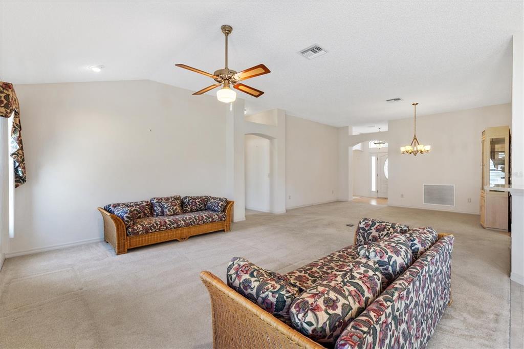 A living room features beige carpeting, two floral wicker sofas, and a ceiling fan — 17723 SE 81ST TIMBERWOOD TERRACE, THE VILLAGES, FL