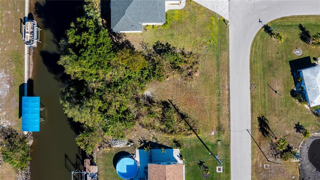 An aerial view shows a vacant residential lot situated between two houses along a canal — 3013 CHAPMAN BOULEVARD, PUNTA GORDA, FL
