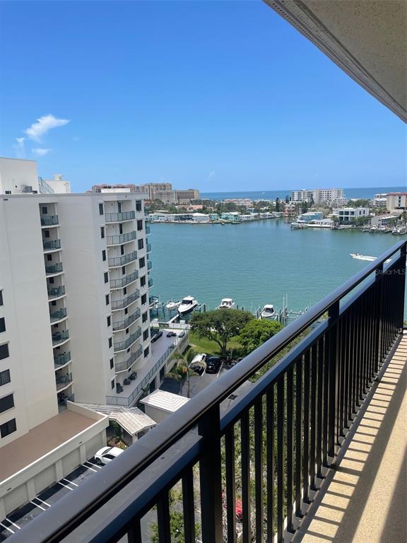 A high-angle view from a balcony overlooking a bay with boats and nearby buildings — 690 ISLAND WAY UNIT 1112, CLEARWATER BEACH, FL