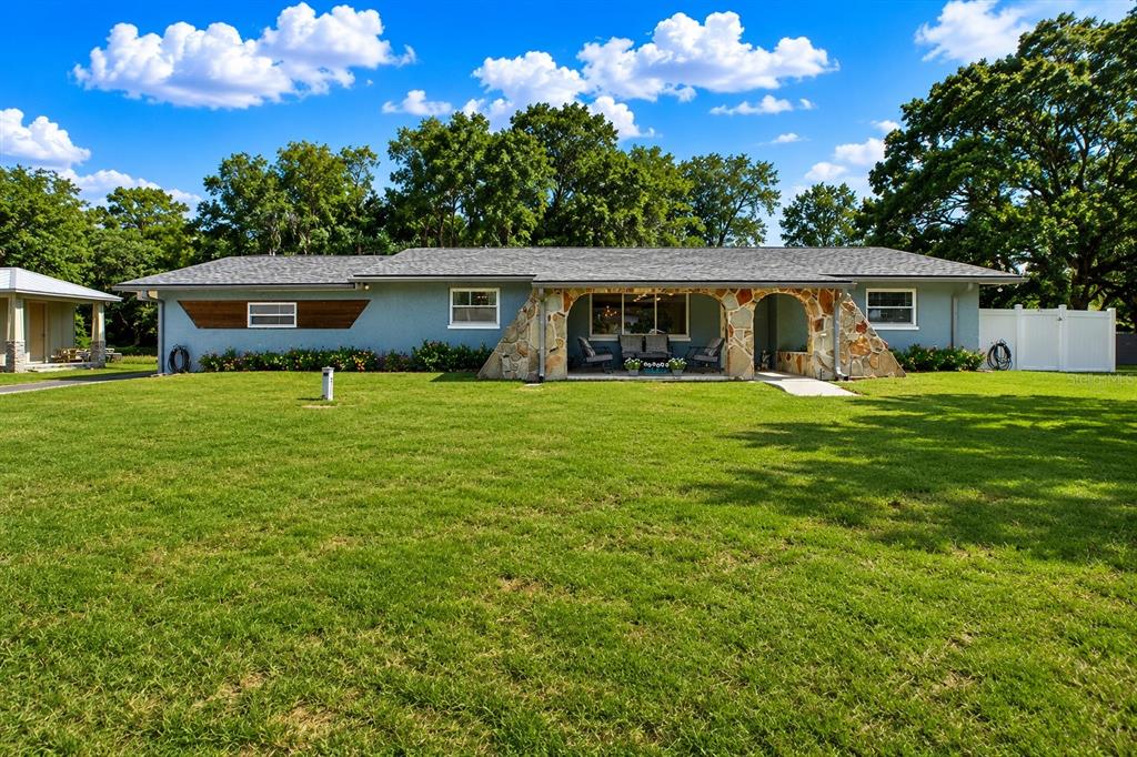 A single-story house with a blue exterior, stone-arched porch, and a large front lawn — 11519 BELMACK BOULEVARD N, ODESSA, FL