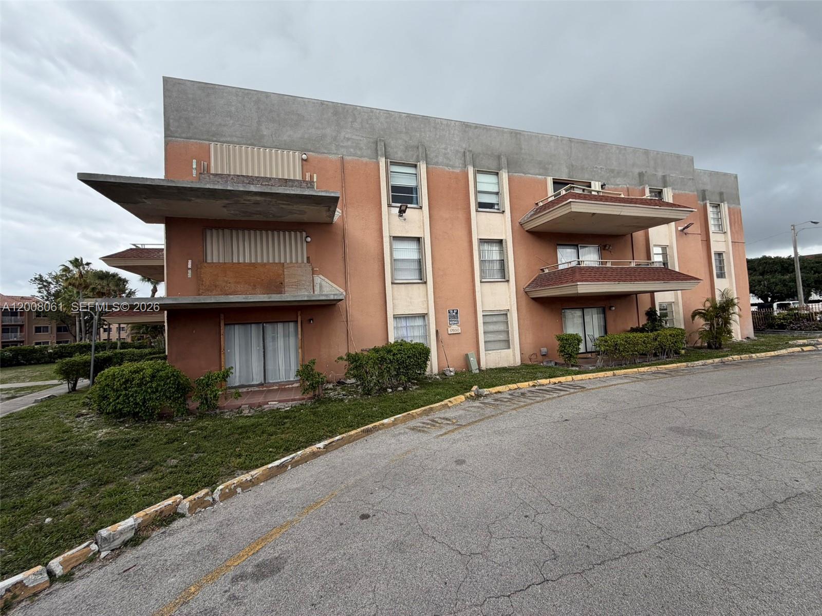 The exterior of a three-story apartment building features balconies, stucco walls, and a paved driveway — 17650 NW 68th Ave # A2008, Hialeah FL 33015, HIALEAH, FL