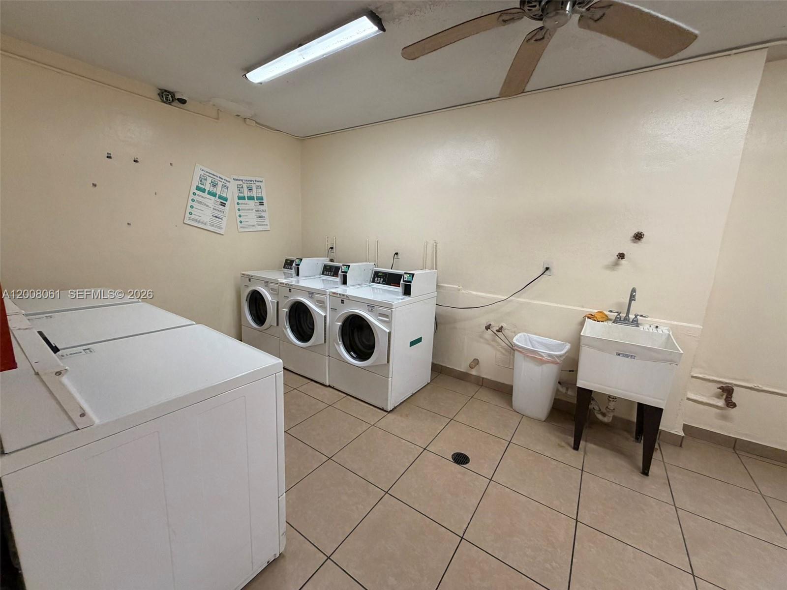 A laundry room features three white dryers, a utility sink, and beige tile flooring — 17650 NW 68th Ave # A2008, Hialeah FL 33015, HIALEAH, FL