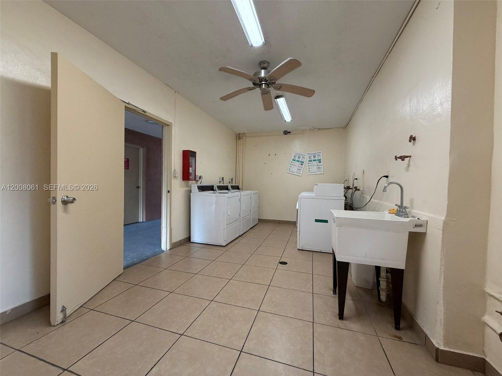 A laundry room features tile flooring, a utility sink, and several white washing machines — 17650 NW 68th Ave # A2008, Hialeah FL 33015, HIALEAH, FL