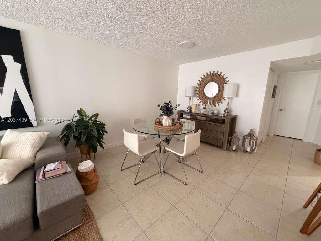 A dining area features a glass-topped table, white chairs, and a wooden sideboard with decor — 4733 NW 97th Ct # 45, Doral FL 33178, DORAL, FL
