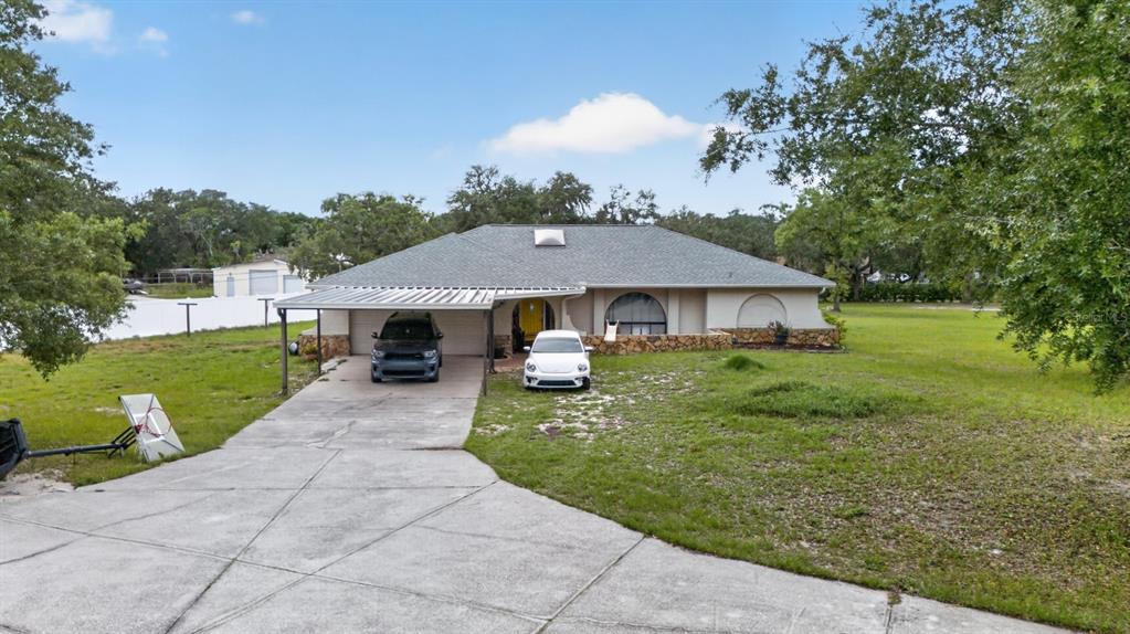 A single-story house with a carport, stone facade, and a large front yard — 11501 MINNIEOLA DRIVE, NEW PORT RICHEY, FL