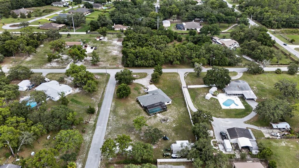 An aerial view shows several houses with swimming pools and large yards in a wooded area — 11501 MINNIEOLA DRIVE, NEW PORT RICHEY, FL