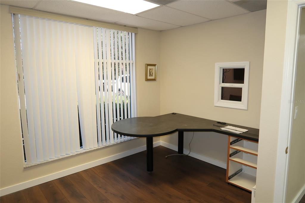An office room features a dark wood floor, a corner desk, and vertical window blinds — 448 S ALAFAYA TRAIL UNIT 4, ORLANDO, FL