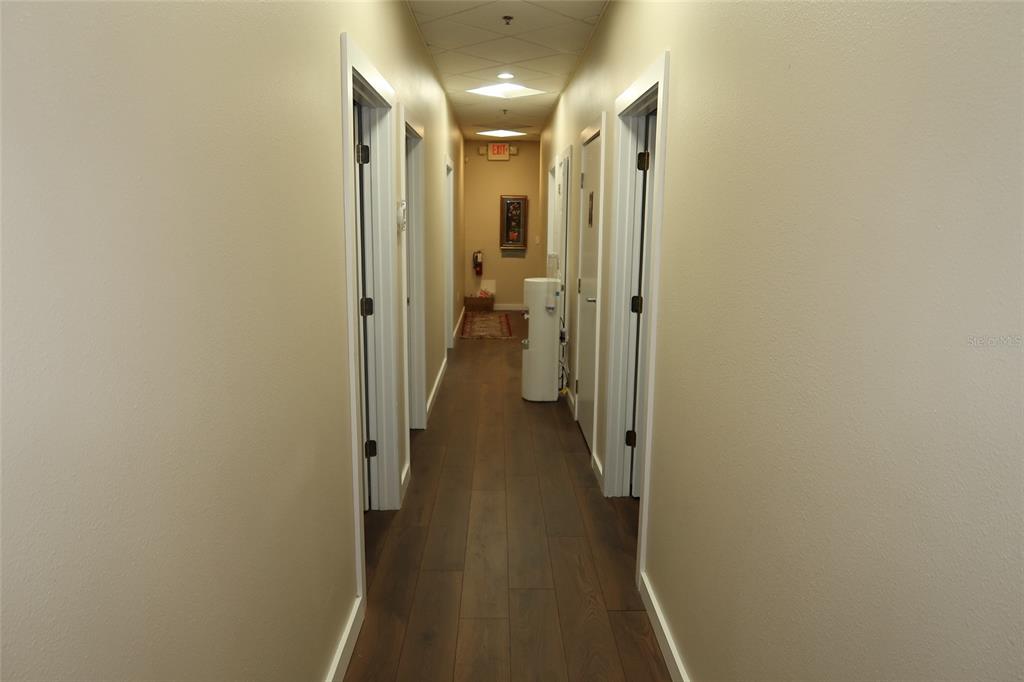 A long hallway features wood-look flooring, beige walls, and multiple white doors — 448 S ALAFAYA TRAIL UNIT 4, ORLANDO, FL