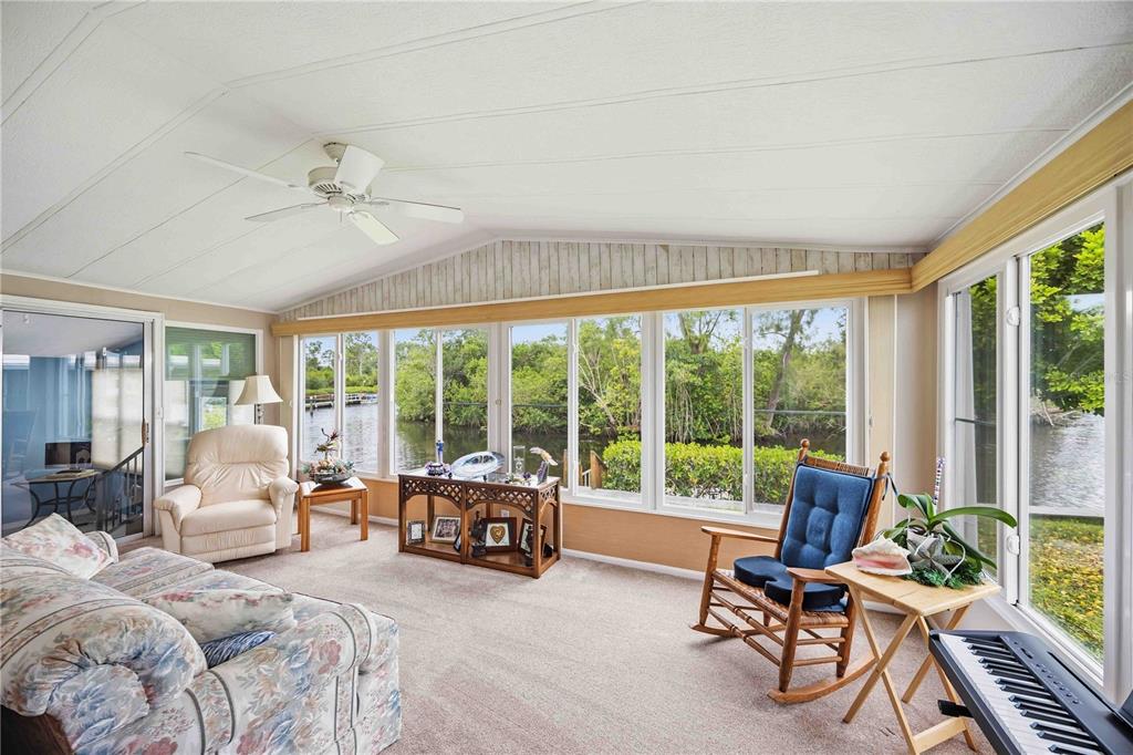 A sunroom with carpeted floors, a ceiling fan, and large windows overlooking a canal — 162 BERMUDA WAY, NORTH PORT, FL