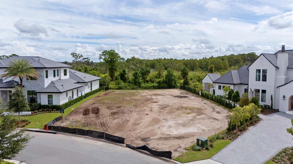 A vacant residential lot sits between two modern houses under a partly cloudy sky — LOT 41, CROMWELL ROAD, ORLANDO, FL