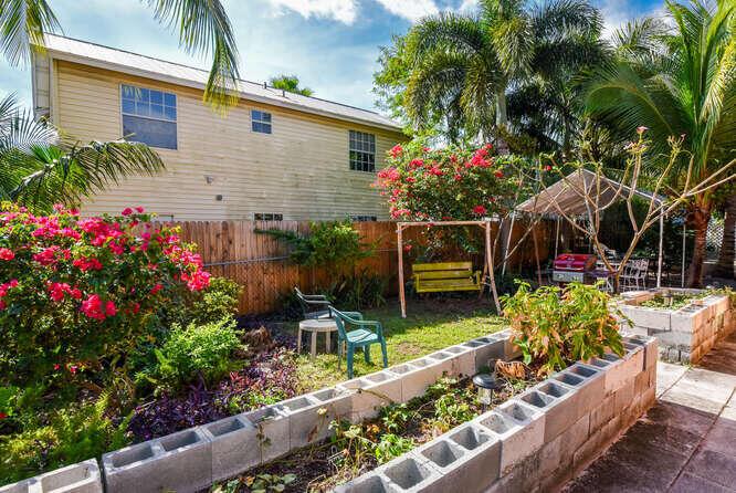 A backyard features a raised cinder block garden bed, a yellow swing, and a wooden fence — 317 N D Street E, FL 33460, FL