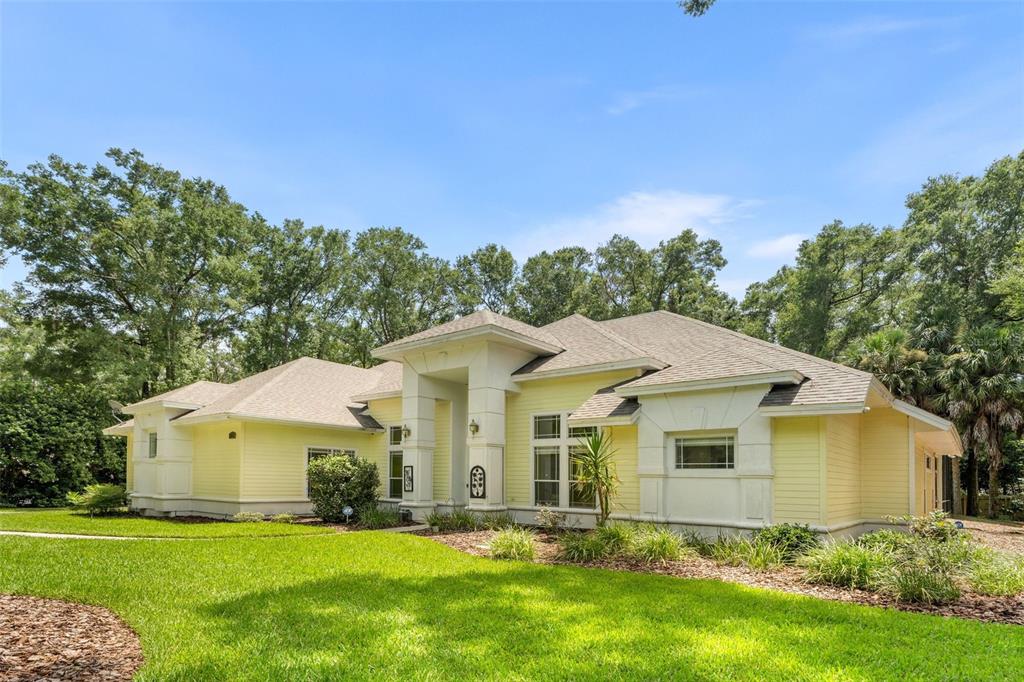 A yellow single-story house with a white trim, a green front door, and a landscaped yard — 9627 SW 40TH LANE, GAINESVILLE, FL
