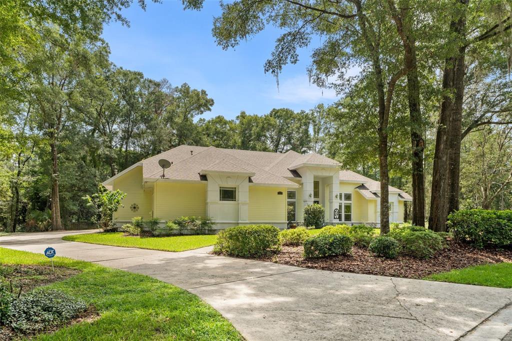 An aerial view shows a house with a screened-in pool surrounded by dense green trees — 9627 SW 40TH LANE, GAINESVILLE, FL