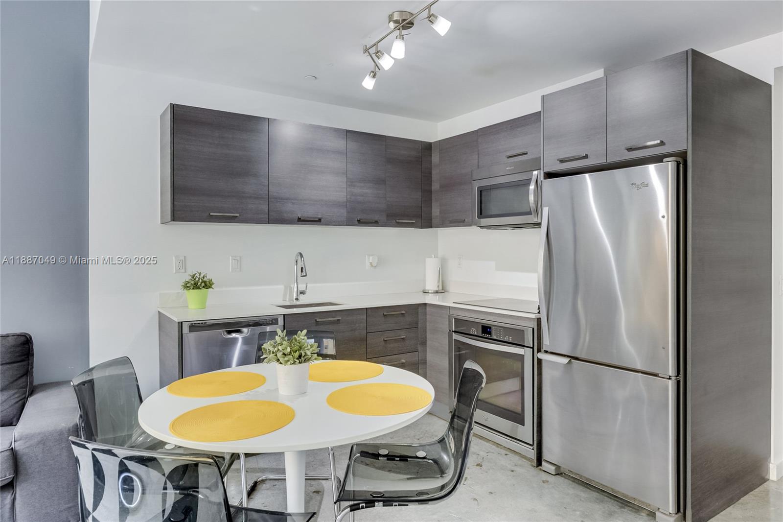 A modern kitchen features dark wood cabinets, stainless steel appliances, and a white dining table — 151 SE 1st St # 1003, Miami FL 33131, MIAMI, FL