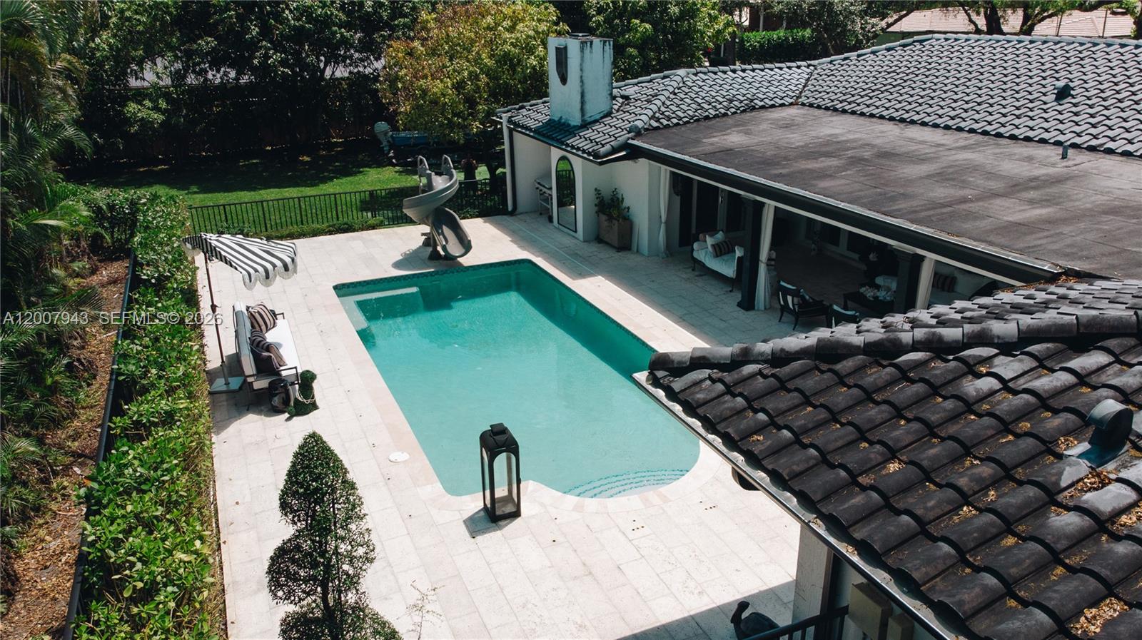 An aerial view shows a swimming pool with a slide next to a house patio — 16241 W Troon Cir, Miami Lakes FL 33014, MIAMI LAKES, FL