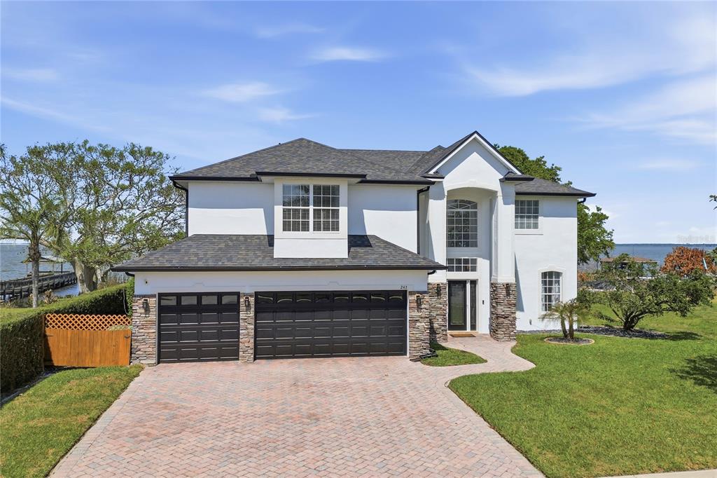 A two-story house with a three-car garage, stone accents, and a brick paver driveway — 243 ZACHARY WADE STREET, WINTER GARDEN, FL