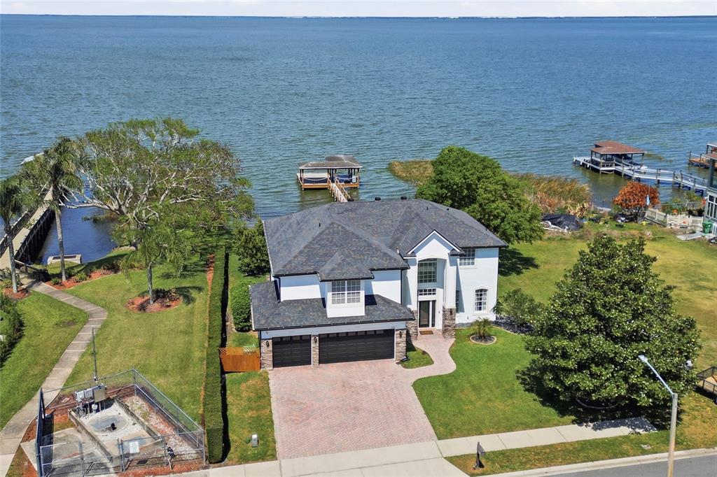 An aerial view shows a two-story house with a three-car garage beside a lake — 243 ZACHARY WADE STREET, WINTER GARDEN, FL