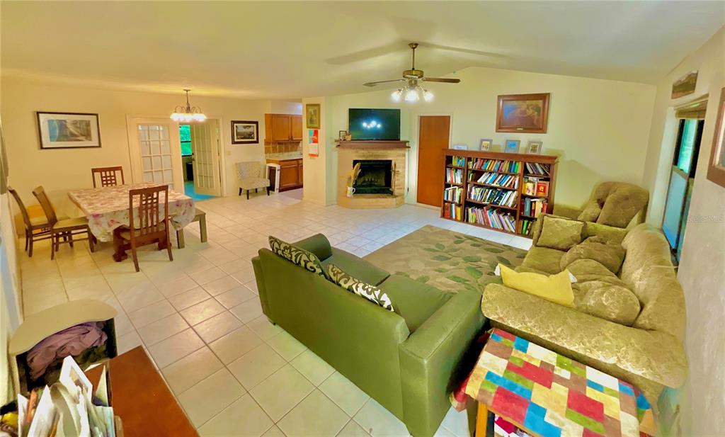 A living room and dining area with tile flooring, a fireplace, and a bookshelf — 5918 COUNTY ROAD 219, MELROSE, FL