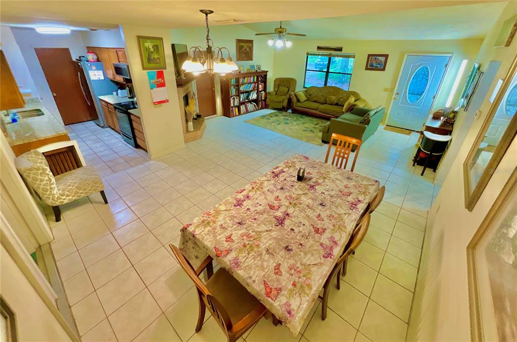 An open-concept living and dining area features tile flooring, a floral tablecloth, and kitchen cabinetry — 5918 COUNTY ROAD 219, MELROSE, FL