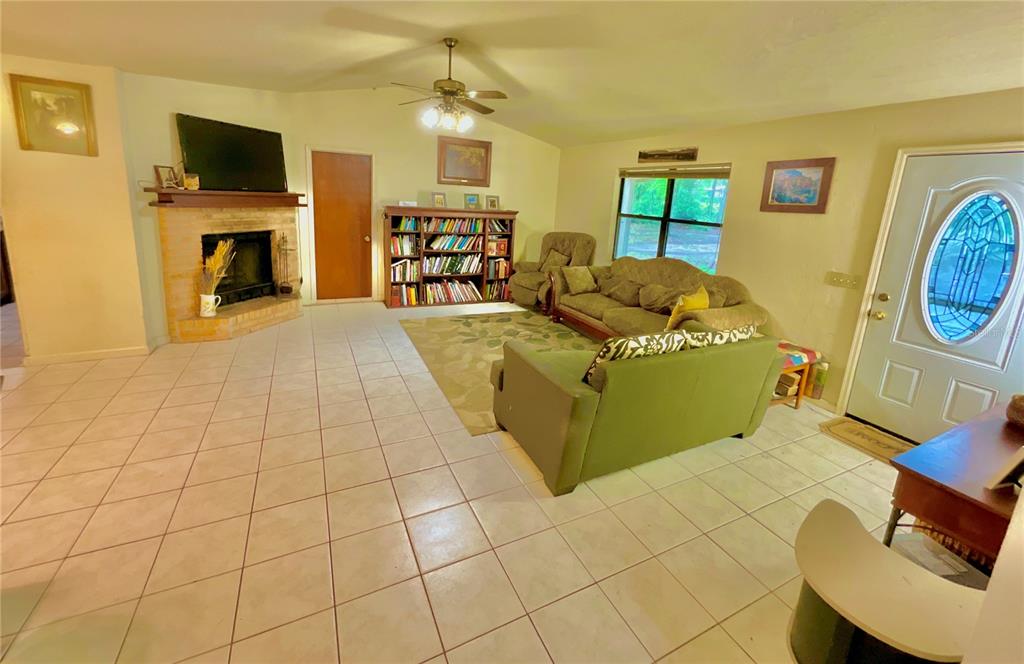 A living room features a brick fireplace, tile flooring, a bookshelf, and a sofa set — 5918 COUNTY ROAD 219, MELROSE, FL