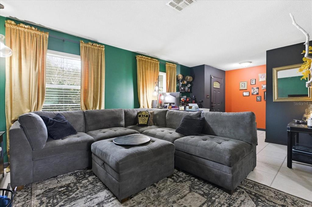 A living room features a large gray sectional sofa, green walls, and an orange accent wall — 4623 CONWAY GARDENS ROAD, ORLANDO, FL