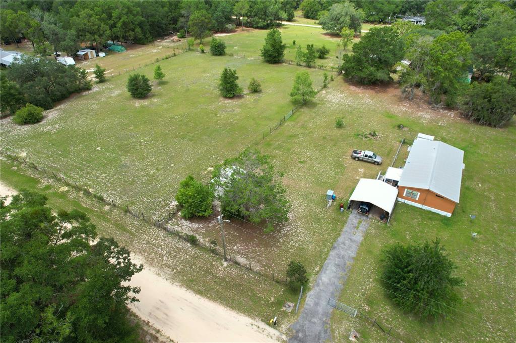 An aerial view shows a house with a carport on a large, fenced, grassy lot — 107 GREEN OAK DRIVE, MELROSE, FL