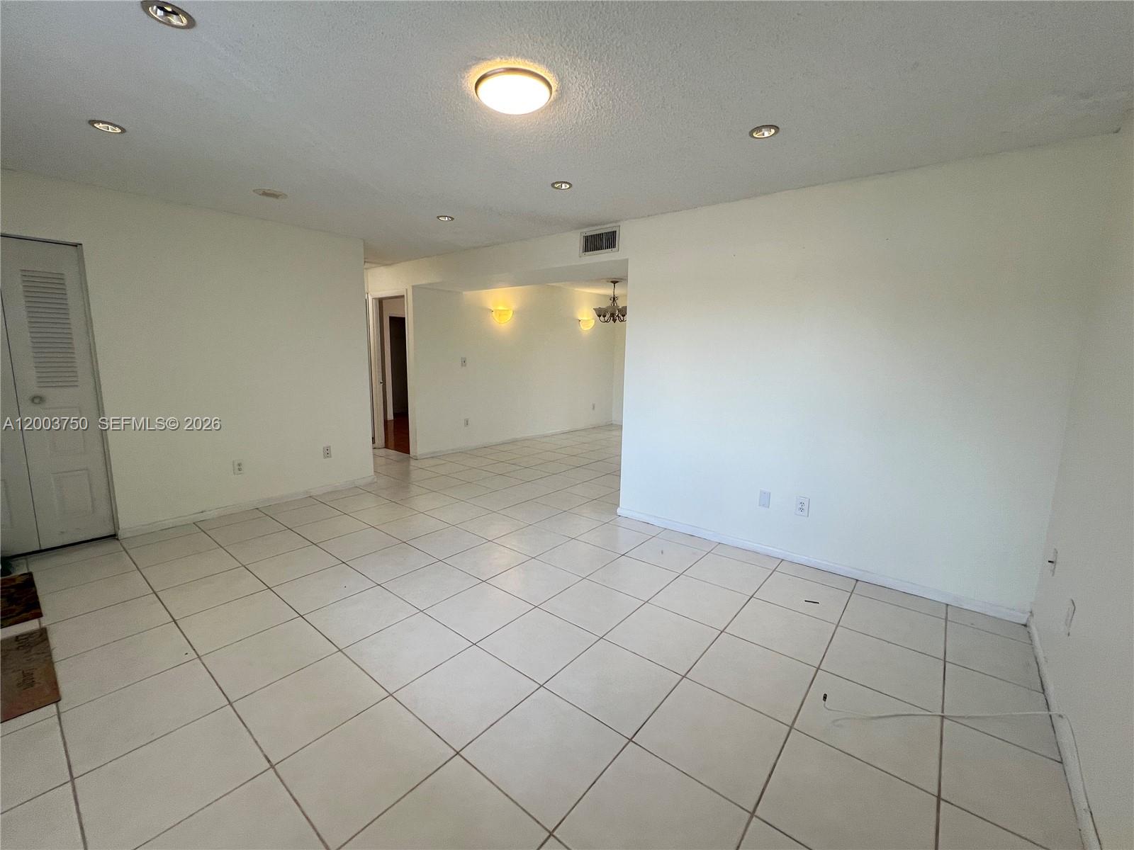 An empty room with white tiled floors, recessed lighting, and a doorway leading to another area — 8401 SW 107th Ave # 322E, Miami FL 33173, MIAMI, FL