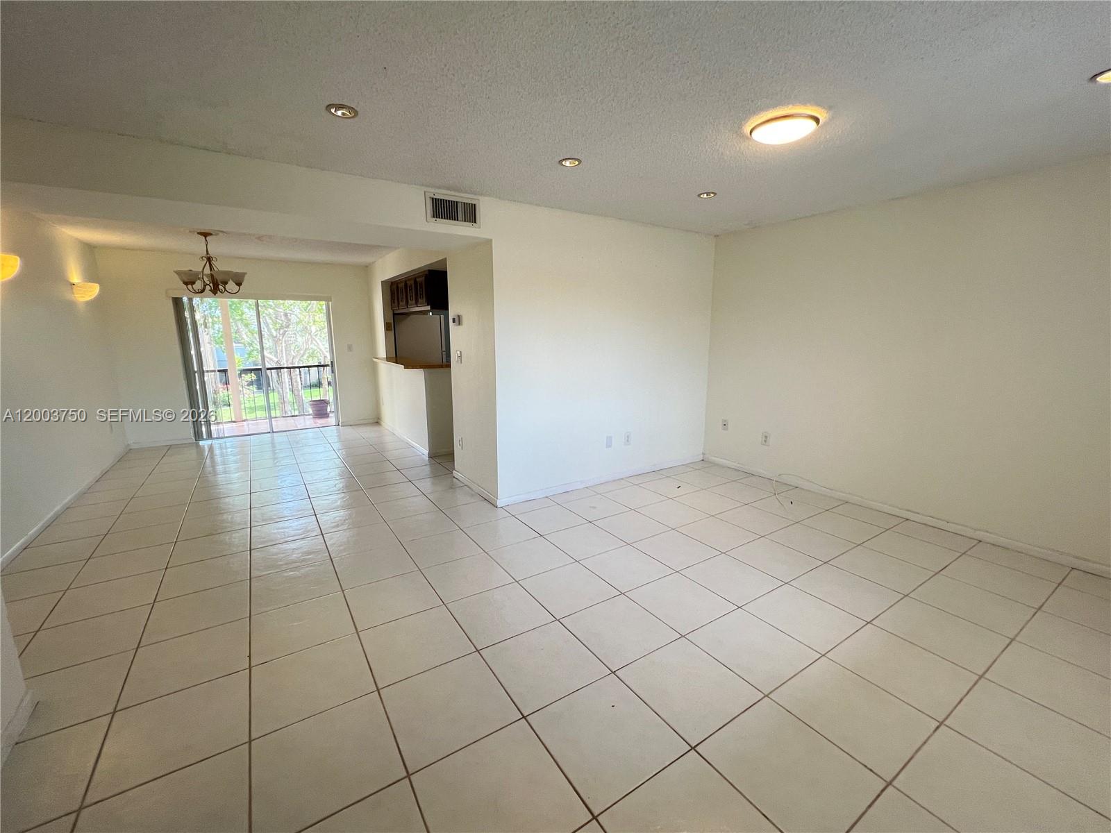 A bright, open-concept living area features white tile flooring, recessed lighting, and a sliding glass door — 8401 SW 107th Ave # 322E, Miami FL 33173, MIAMI, FL