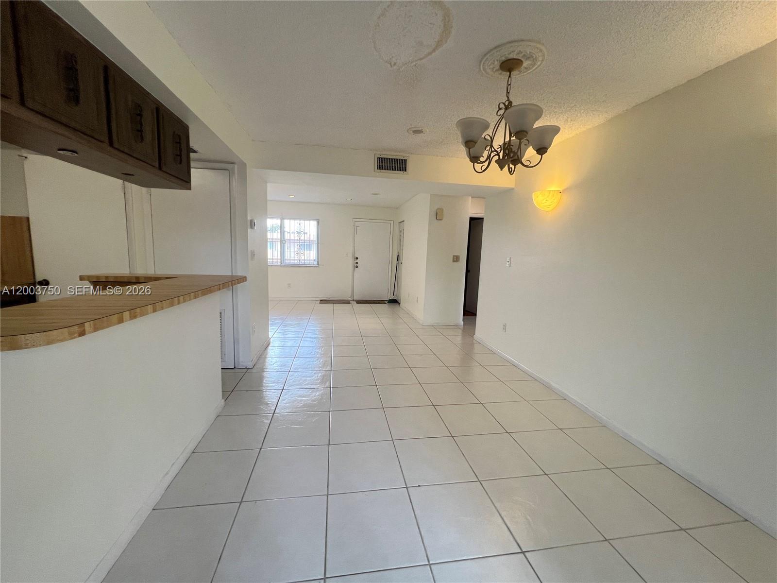 An open-concept living and dining area features white tile flooring and a hanging chandelier — 8401 SW 107th Ave # 322E, Miami FL 33173, MIAMI, FL