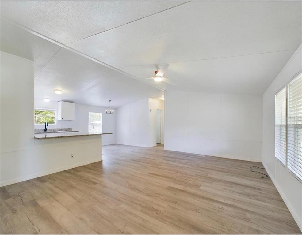 An open-concept living area with light wood-look flooring, white walls, and a kitchen breakfast bar — 12250 NW 7TH PLACE, OCALA, FL