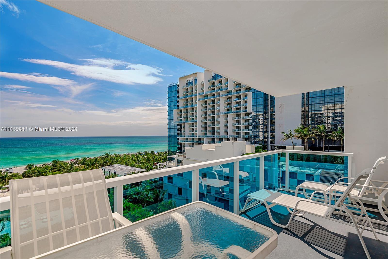 A balcony with patio furniture overlooks the ocean and nearby high-rise buildings — 2301 Collins Ave # 938, Miami Beach FL 33139, MIAMI BEACH, FL