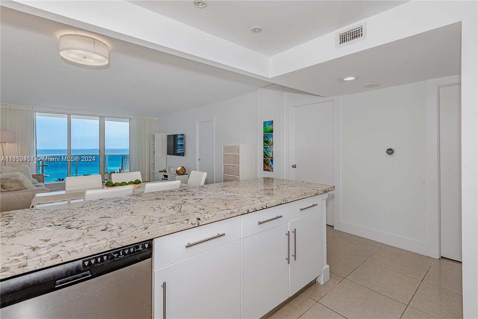 A kitchen island with granite countertops overlooks a living area with ocean views — 2301 Collins Ave # 938, Miami Beach FL 33139, MIAMI BEACH, FL