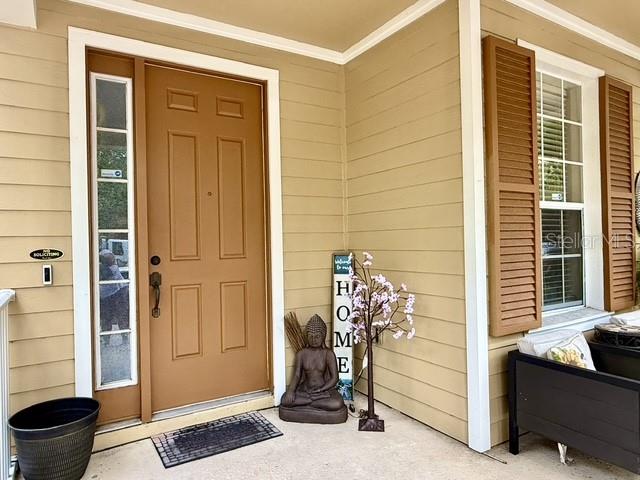 A tan front door with a side window and a Buddha statue on the porch — 10378 LAKE DISTRICT LANE UNIT 2B, ORLANDO, FL