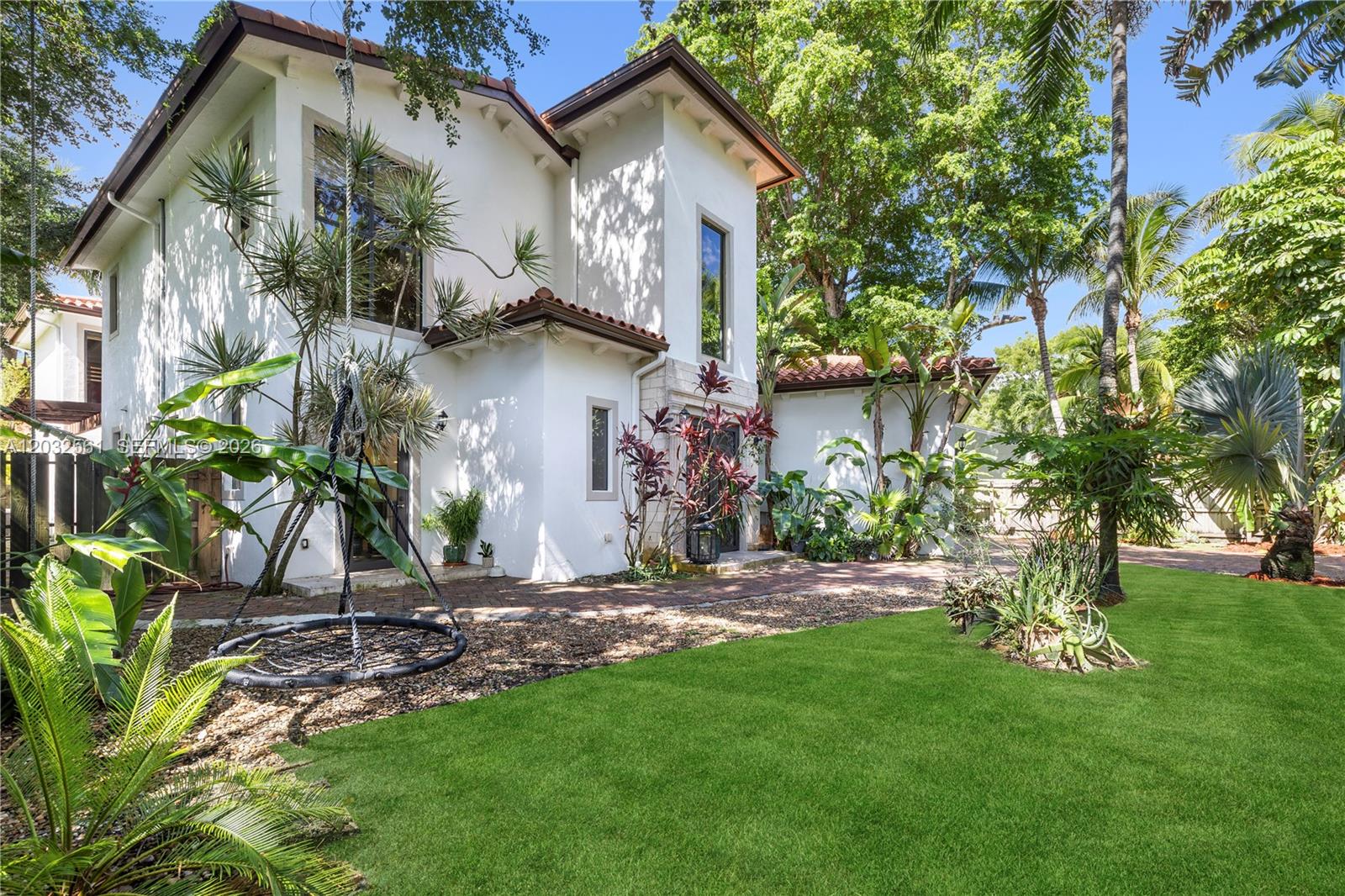 A two-story white stucco house with a tile roof sits beside a grassy yard — 6550 SW 75th Ter, South Miami FL 33143, SOUTH MIAMI, FL