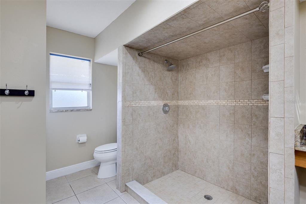 A bathroom features a tiled walk-in shower, a toilet, and a window with blinds — 23230 GOLDCOAST AVENUE, PUNTA GORDA, FL