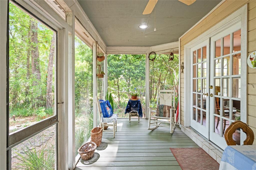 A screened-in porch with a green wooden floor, a rocking chair, and glass French doors — 2132 PALM VISTA DRIVE, APOPKA, FL