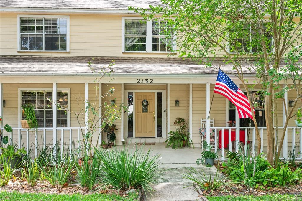 A two-story house with yellow siding, a front porch, and an American flag — 2132 PALM VISTA DRIVE, APOPKA, FL