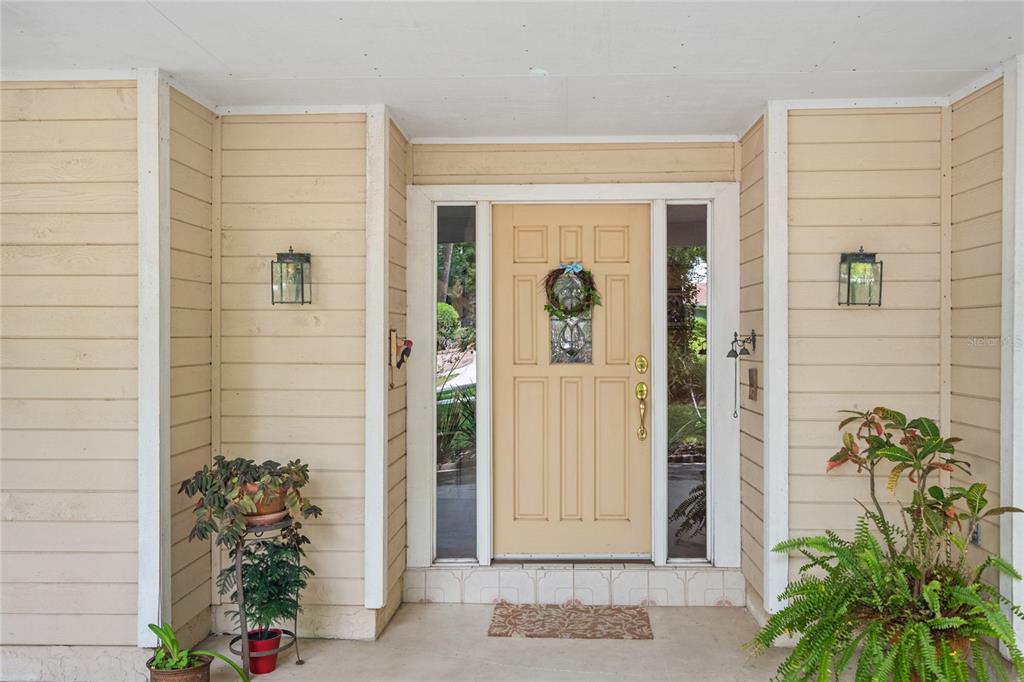 A front entryway with a light yellow door, sidelights, and exterior wall-mounted lanterns — 2132 PALM VISTA DRIVE, APOPKA, FL