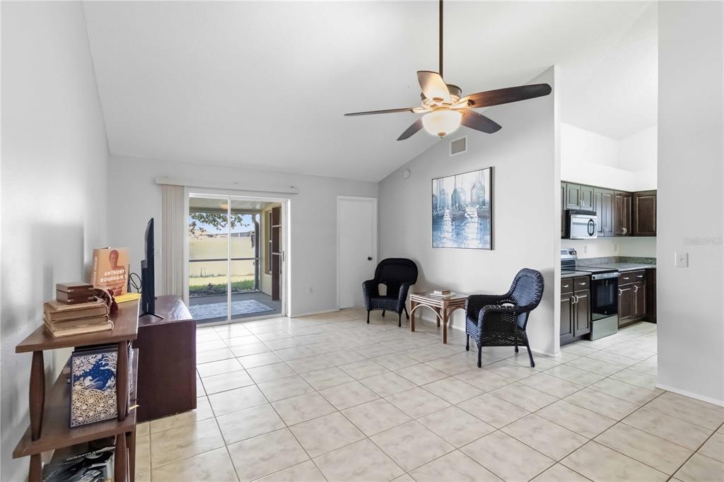 A living room with tile floors, a ceiling fan, and an adjacent kitchen — 13437 BEECHBERRY DRIVE, RIVERVIEW, FL