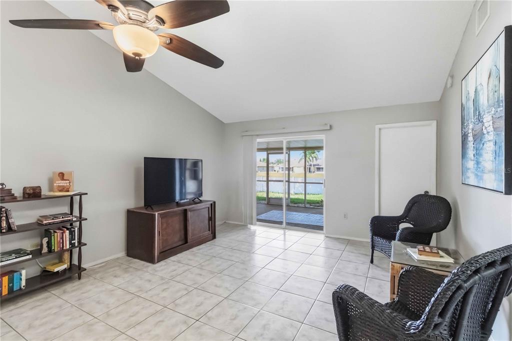 A living room with tile floors, a ceiling fan, a television console, and wicker chairs — 13437 BEECHBERRY DRIVE, RIVERVIEW, FL